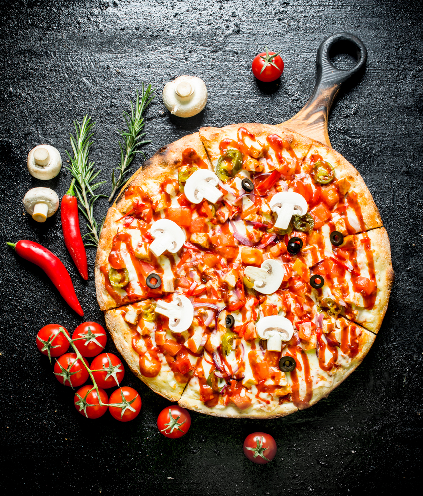 Pizza with chili pepper, tomatoes and mushrooms. On black rustic background. Pizza with chili pepper, tomatoes and mushrooms.