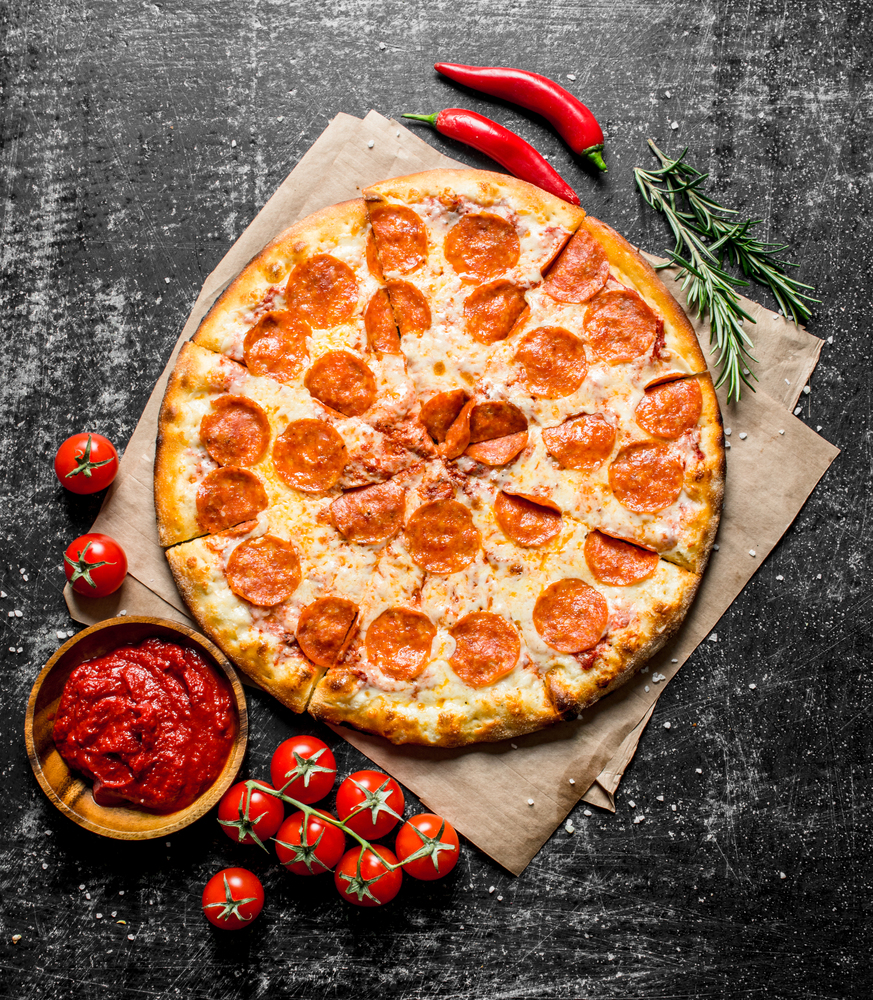 Pepperoni pizza with chili, rosemary and tomatoes. On dark rustic background. Pepperoni pizza with chili, rosemary and tomatoes.
