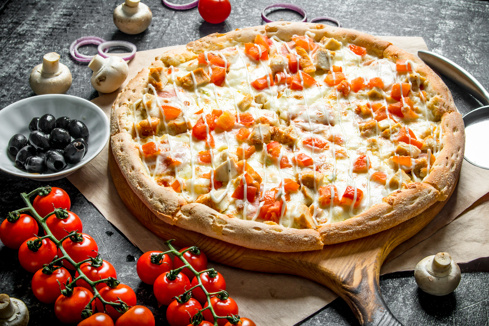 Fragrant pizza with chicken and tomatoes. On dark rustic background. Fragrant pizza with chicken and tomatoes.