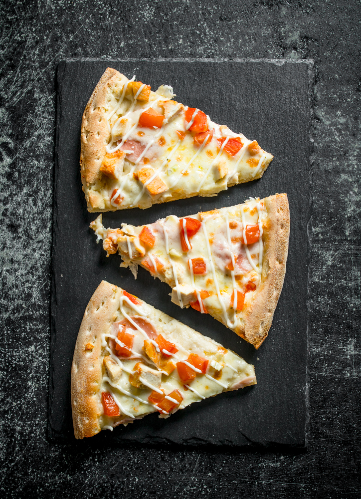 Slices of fragrant pizza with chicken. On dark rustic background. Slices of fragrant pizza with chicken.