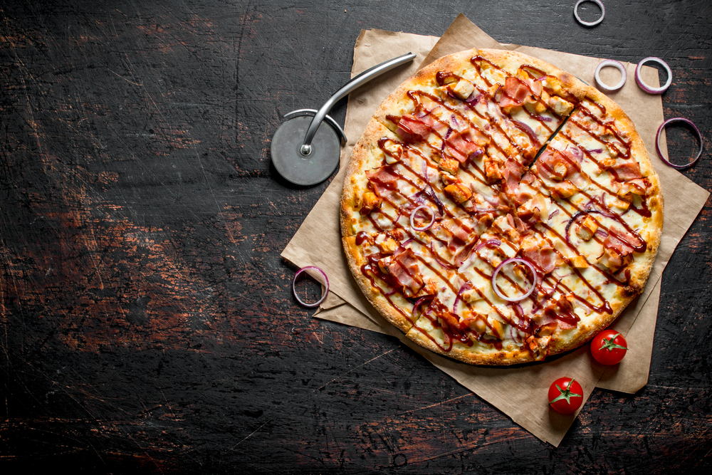 Barbecue pizza with bacon, chicken and sauce. On dark rustic background. Barbecue pizza with bacon, chicken and sauce.