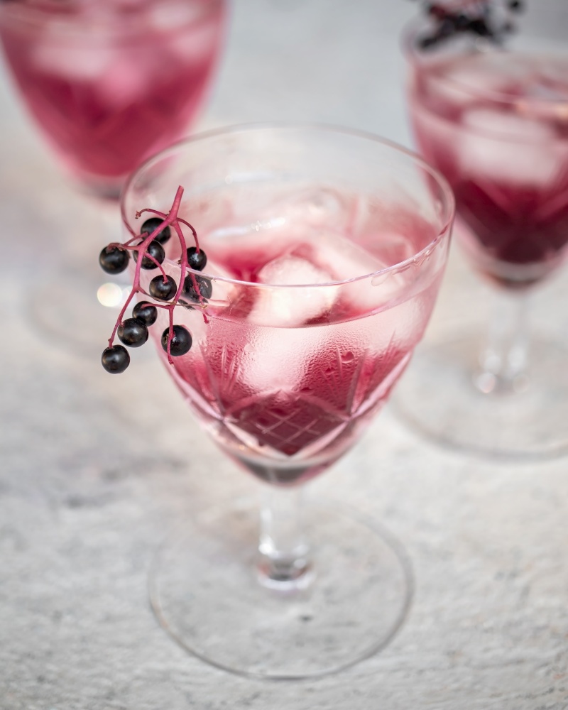 Water with ice and black elder syrup, decorated with elderberries