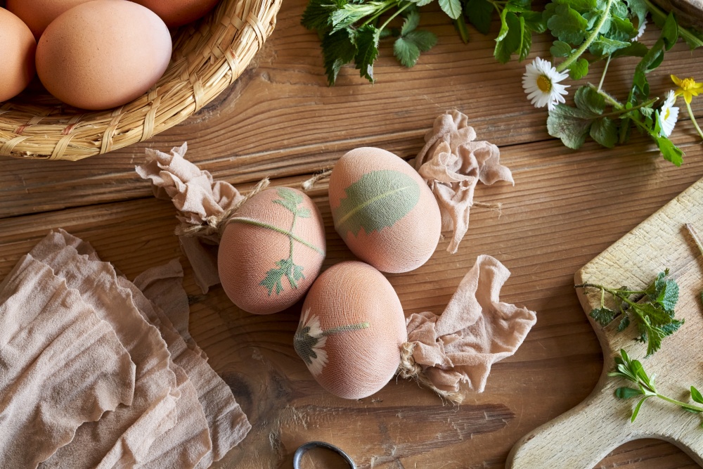 Easter eggs with fresh herbs attached to them, ready to be dyed with onion peels