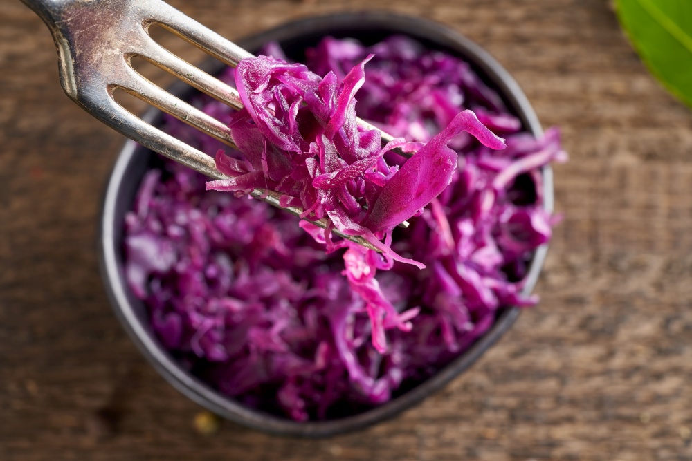 Red fermented cabbage on a fork, close up