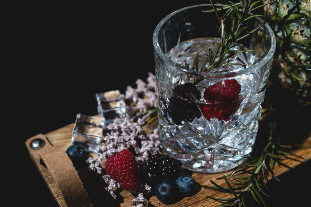 alcoholic drink with berries and ice on a old wooden table