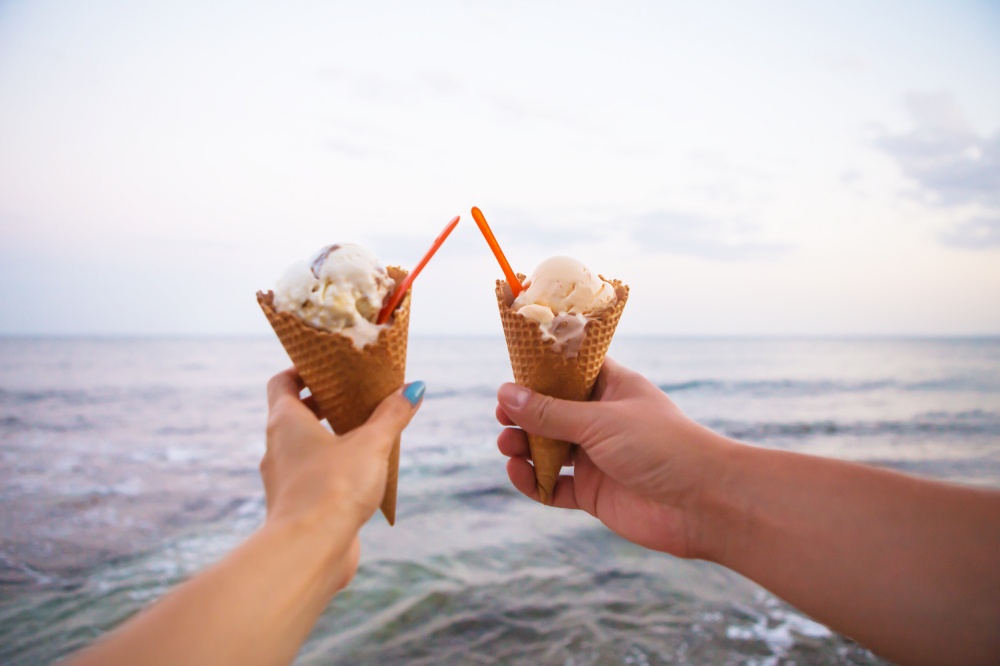 two hands holding tasty ice cream on a summer beach.. two hands holding tasty ice cream on a summer beach