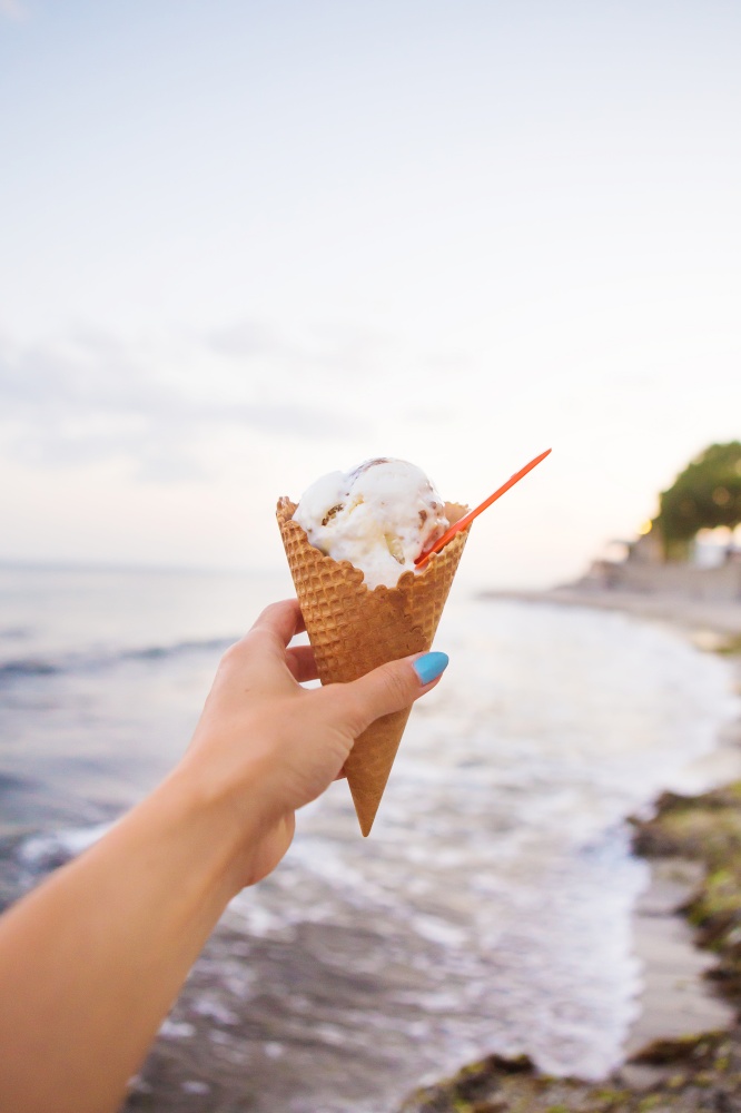one hand holds tasty ice cream on a summer beach.. one hand holds tasty ice cream on a summer beach