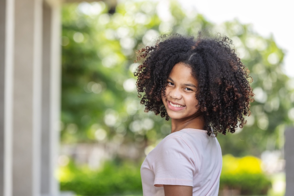 portrait of African American curly hair girl smiling with happiness and looking at camera.Nature background.