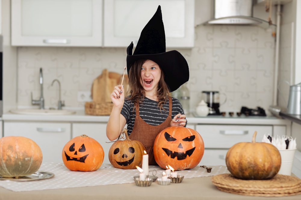 Happy halloween. Cute little girl in witch costume with carving pumpkin. Happy family preparing for Halloween. girl lights candles.. Happy halloween. Cute little girl in witch costume with carving pumpkin. Happy family preparing for Halloween. girl lights candles