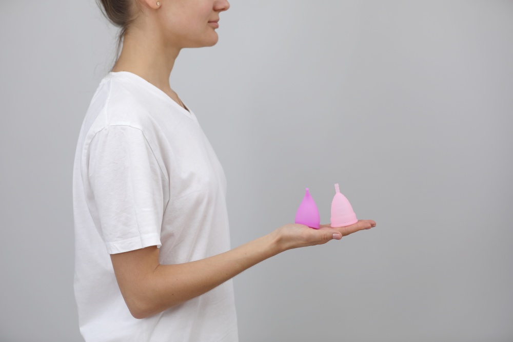 close up of woman holding in her hands different kinds of pink and purple menstrual cups. woman&rsquo;s choice. Gynecology concept.. close up of woman holding in her hands different kinds of pink and purple menstrual cups. woman&rsquo;s choice. Gynecology concept