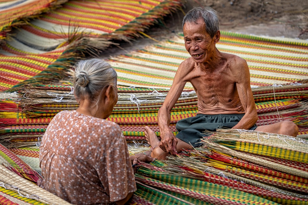 Top view of old Vietnamese lover craftsman making the traditional vietnam mats with happiness action in the old traditional village at dinh yen, dong thap, vietnam, tradition artist concept