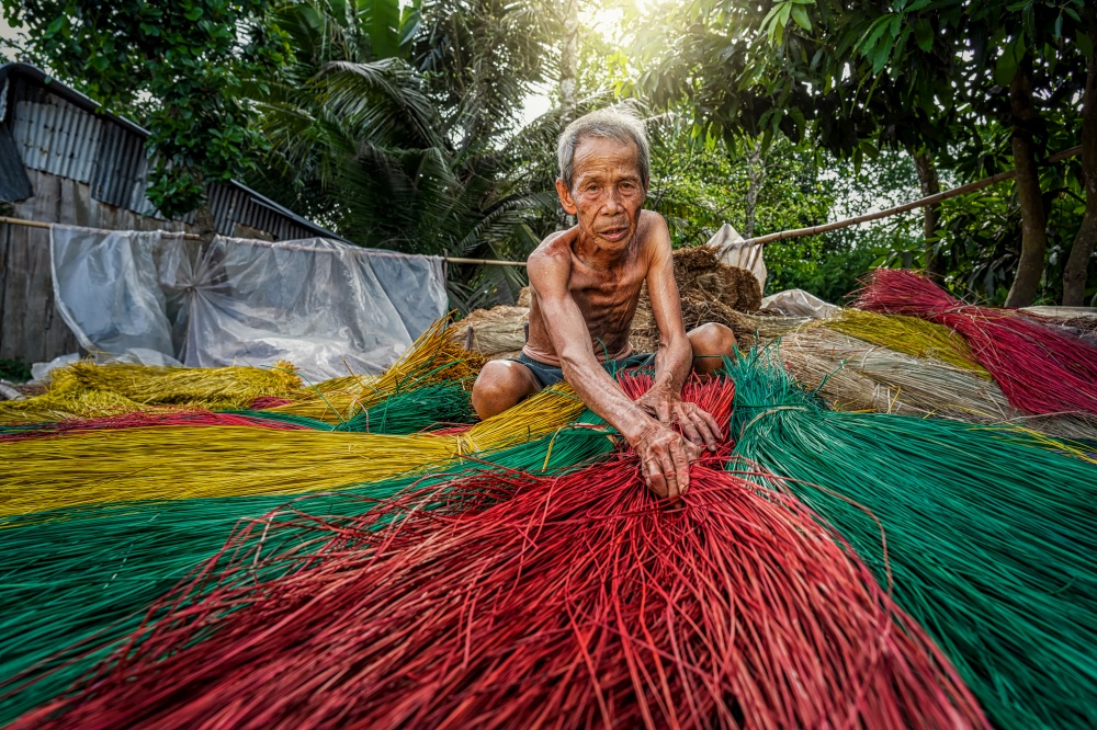 Vietnamese Old man craftsman making the traditional vietnam mats in the old traditional village at dinh yen, dong thap, vietnam, tradition artist concept