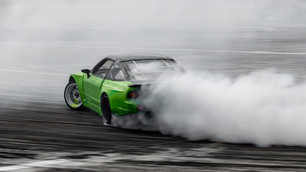 Blurred car drifting, Professional driver drive car drifting on asphalt street road race track, Automobile or automotive drift car with lot of smoke from burning tire on speed track.