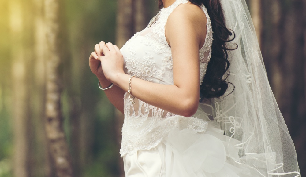 Beautiful bride stand waiting  bridegroom outdoors in a forest