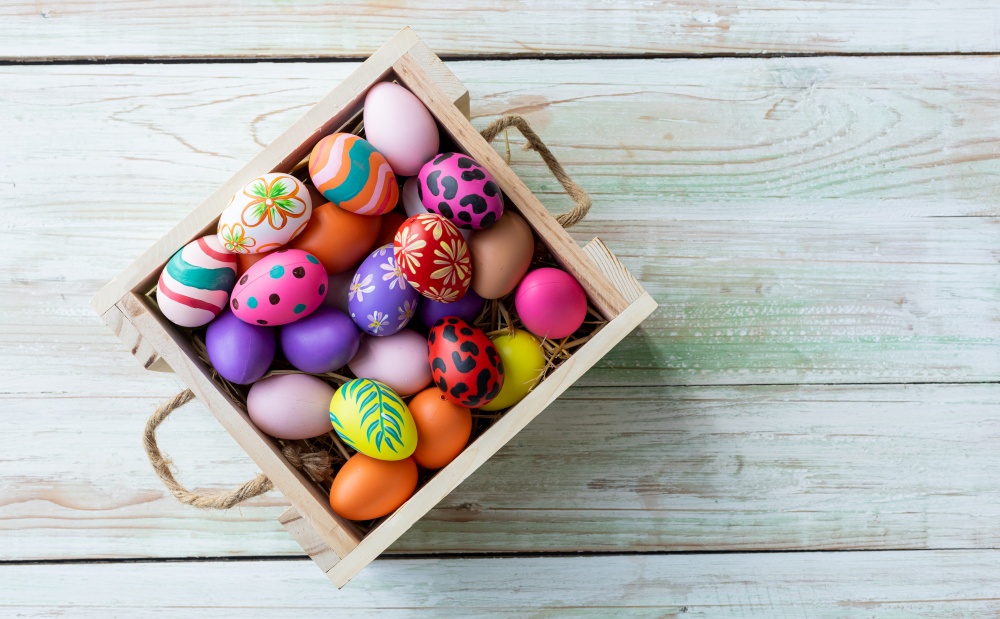 Easter holiday concept,Colorful Easter eggs in basket on white pastel color rustic wood background with space.