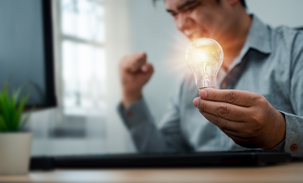 Businessman holding lightbulb and feeling delighted and excited by new innovation and ideas for success business panels.Concept of innovation creative technology ideas for Business solution