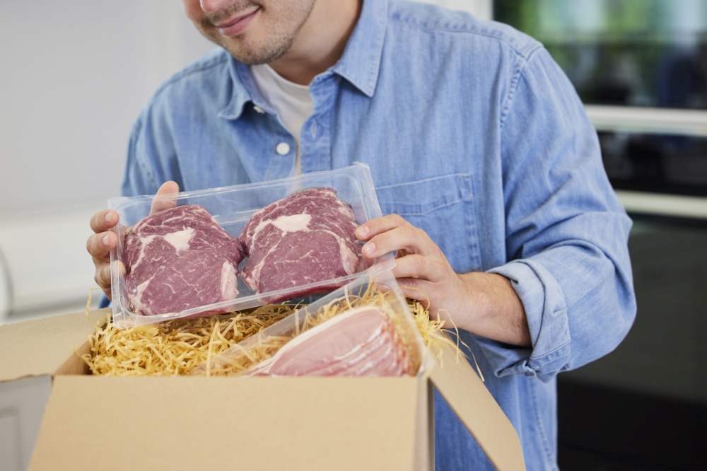 Man Unpacking Online Luxury Meat Order Of Steak And Bacon Delivered To Home