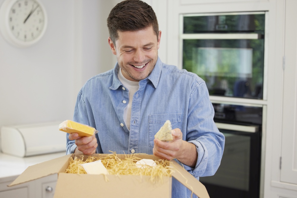 Man Unpacking Online Luxury Cheeses Delivered To Home
