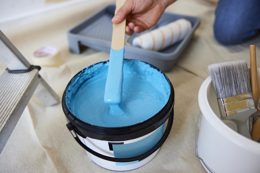 Close Up Of Man Stirring Paint Before Decorating Room At Home