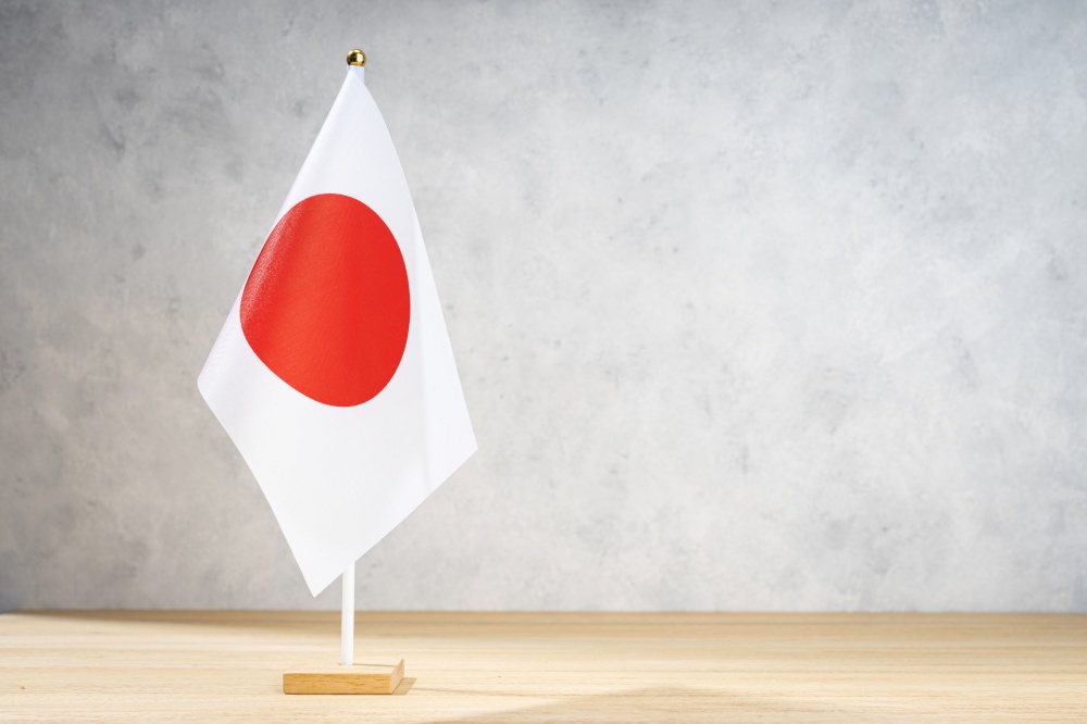 Japan table flag on white textured wall. Copy space for text, designs or drawings