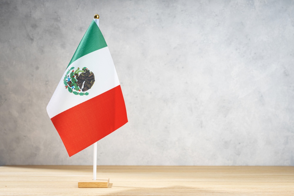 Mexico table flag on white textured wall. Copy space for text, designs or drawings