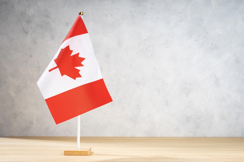 Canada table flag on white textured wall. Copy space for text, designs or drawings