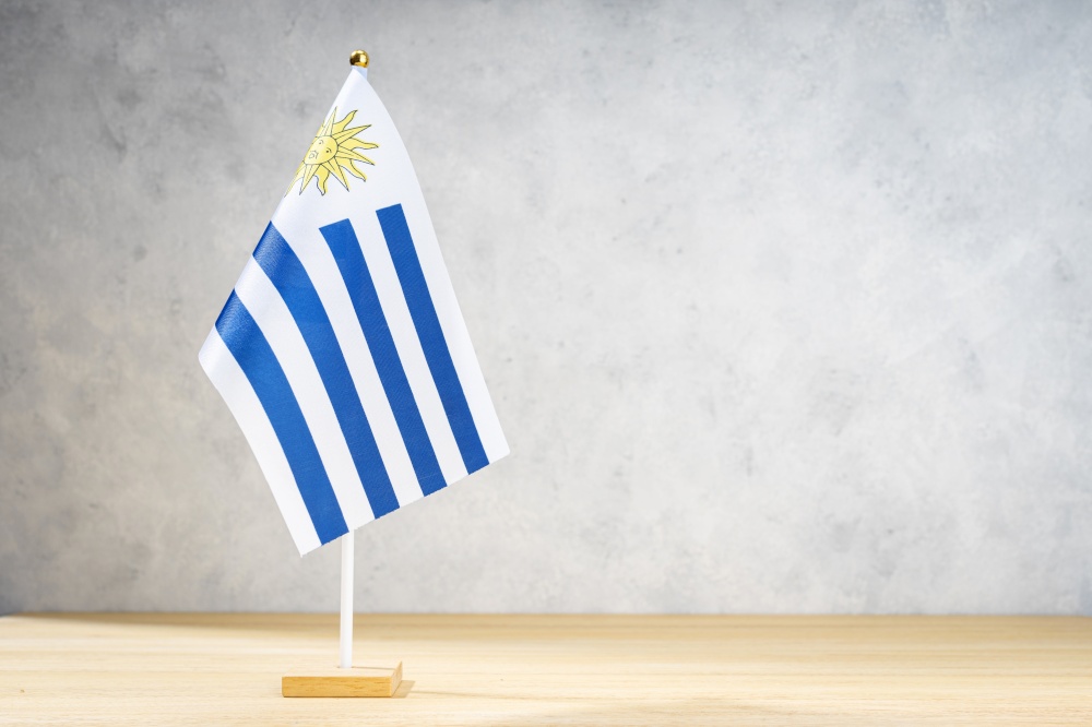 Uruguay table flag on white textured wall. Copy space for text, designs or drawings