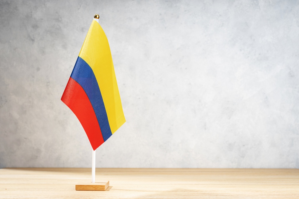 Colombia table flag on white textured wall. Copy space for text, designs or drawings