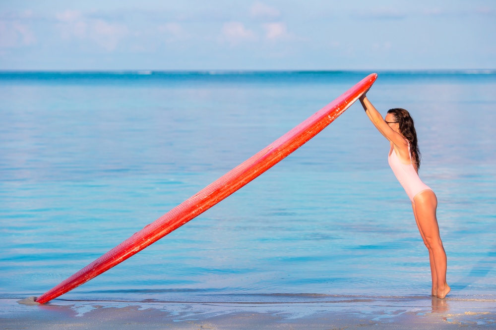 Surf woman on seashore with her surfboard on Maldives. Happy beautiful surfer girl at the beach with her surfboard