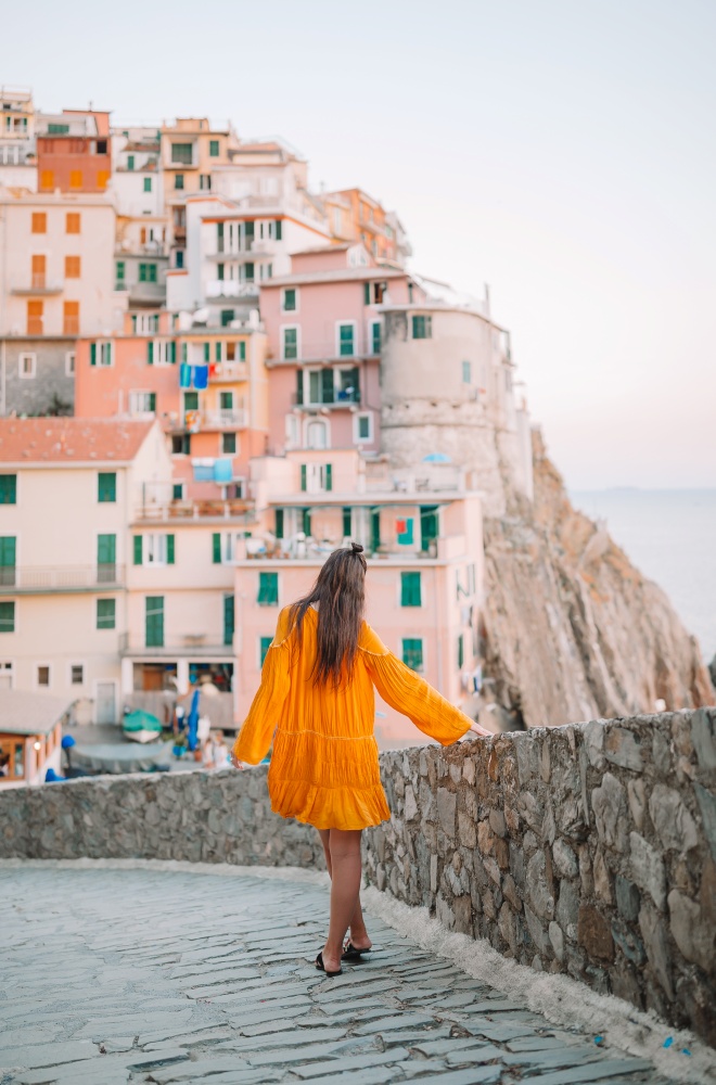 Young woman with view of amazing village of Manarola, Cinque Terre, Italy. European vacation.. Tourist looking at scenic view of Manarola, Cinque Terre, Liguria, Italy