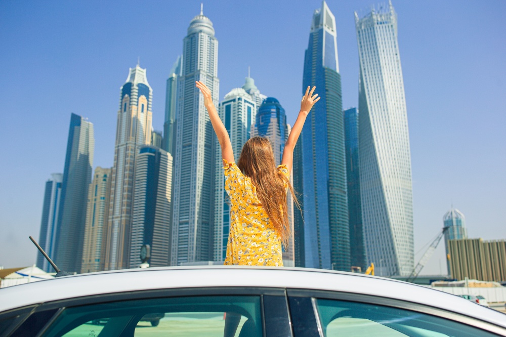 Kids summer vacation. Teenager girl on car vacation on background of skyscrapers in Dubai. Summer car trip and adorable girl on vacation