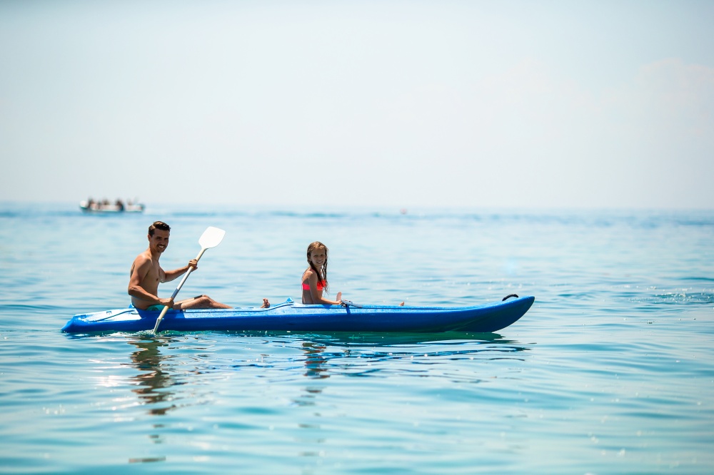 Young father and little kid kayaking at the sea. Sporty attractive family kayaking on sea together