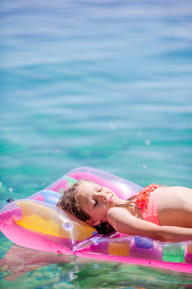 Adorable girl relaxing on inflatable air mattress on summer day. Adorable girl on inflatable air mattress in the sea