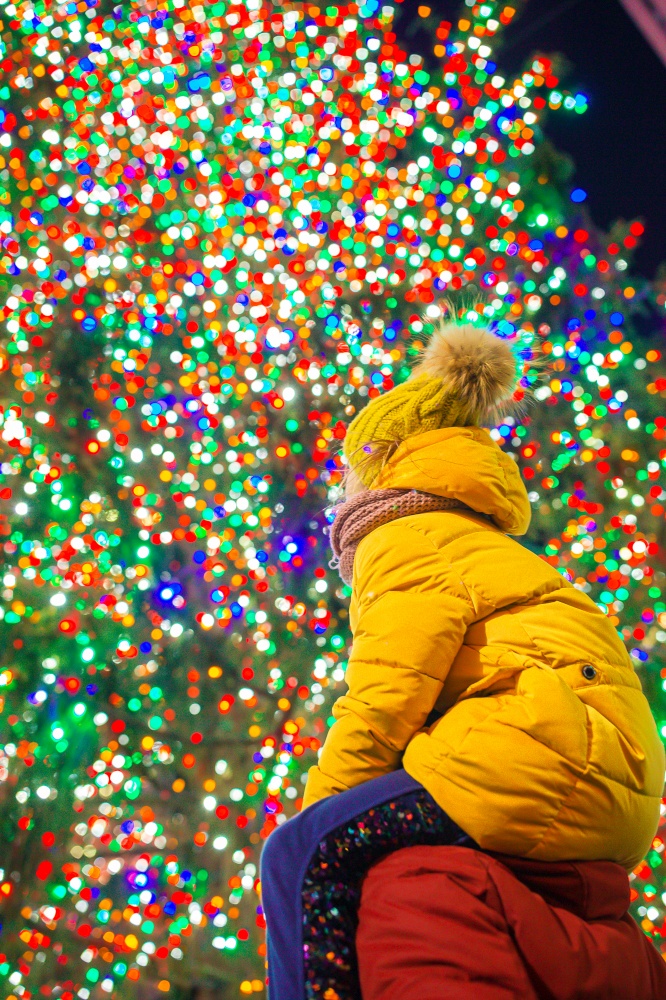 Family of father and kid on the background of the Rockefeller Christmas tree in New York. Beautiful Christmas Tree at Rockefeller center. Happy girl with dad on the background of the Rockefeller Christmas tree in New York
