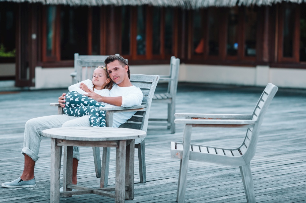 Family enjoy vacation and relaxing in outdoors cafe. Happy father and his adorable little daughter relax at tropical vacation