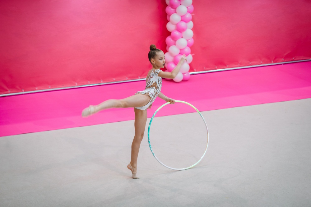 Amazing little gymnast girl with hoop on the carpet on the competition. Little gymnast training on the carpet and ready for competitions