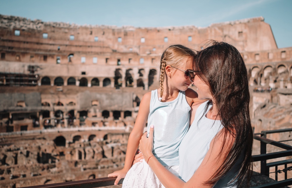 Happy family in Rome background of Coliseum. Family portrait at famous places in Europe. Young mother and little girl hugging in Coliseum, Rome, Italy.