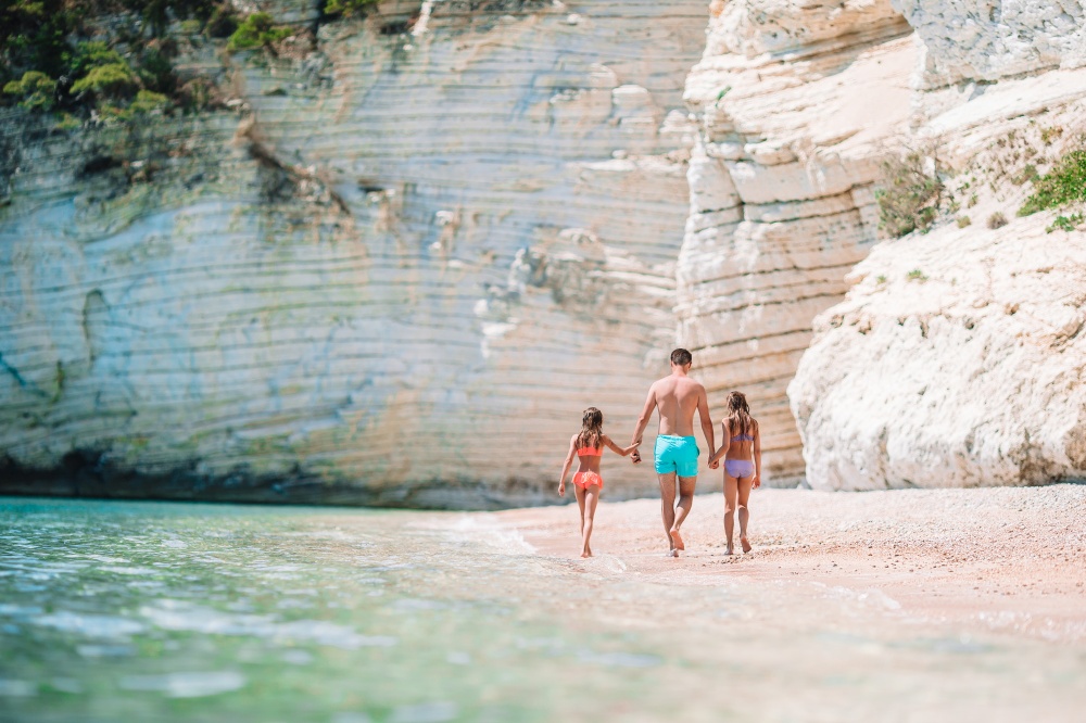 Young dad and his little daughters walking on the beach. Father and two daughters on Caribbean beach