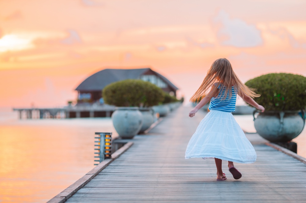 Silhouette of adorable little girl on a beach at sunset. Silhouette of adorable little girl on wooden jetty at sunset