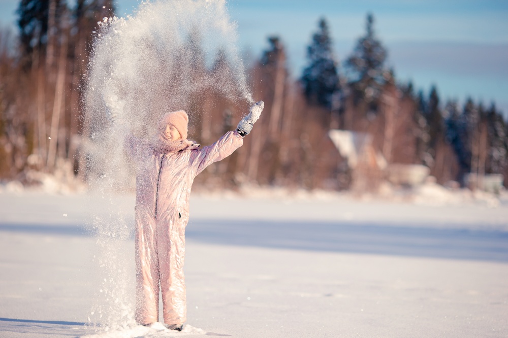 Portrait of little girl enjoying winter games outdoors. Adorable little happy girl sledding in winter snowy day.