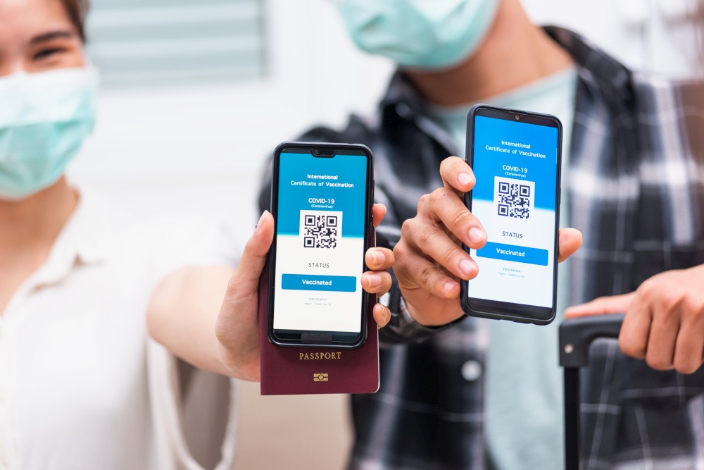 Asian young couple woman and man ready to travel showing digital vaccine health passport certificate app in smartphone screen during coronavirus pandemic, Mobile app of virus covid-19 vaccination