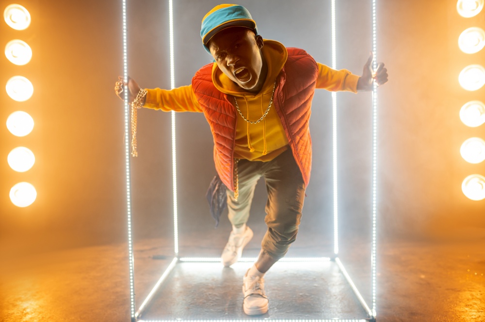Stylish rapper on the stage with illuminated cube. Hip-hop performer, rap singer, break-dance performing, entertainment lifestyle. Stylish rapper on the stage with illuminated cube