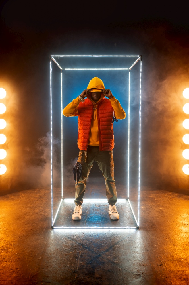 Stylish rapper poses in illuminated cube. Hip-hop performer, rap singer, break-dance performing, entertainment lifestyle. Stylish rapper poses in illuminated cube