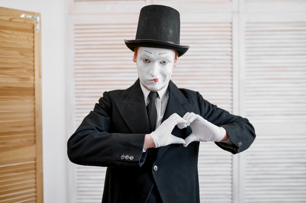 Male mime artist, love heart gesture, parody. Pantomime theater, comedian, positive emotion, humour performance, funny face mimic and grimace. Male mime artist, love heart gesture, parody