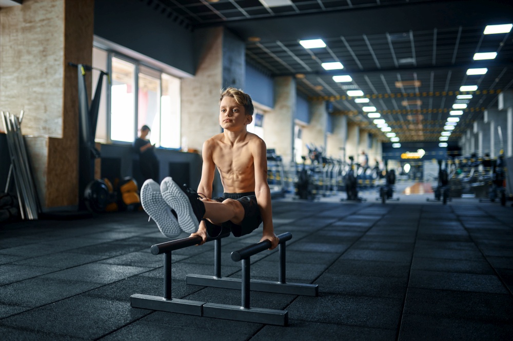 Athletic boy doing ABS exercise on uneven bars in gym. Youngster on training in sport club, healthcare and healthy lifestyle, schoolboy on aerobics workout, sportive youth. Boy doing ABS exercise on uneven bars in gym