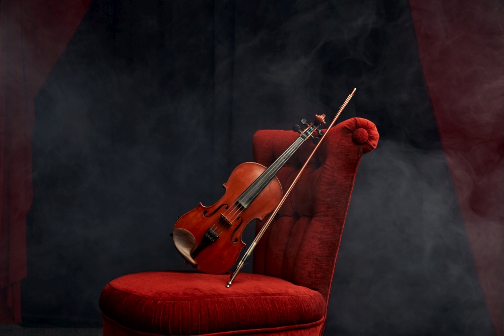 Violin in retro style and bow on the chair, nobody. Classical string musical instrument, music art, wooden viola, dark background. Violin in retro style and bow on the chair, nobody