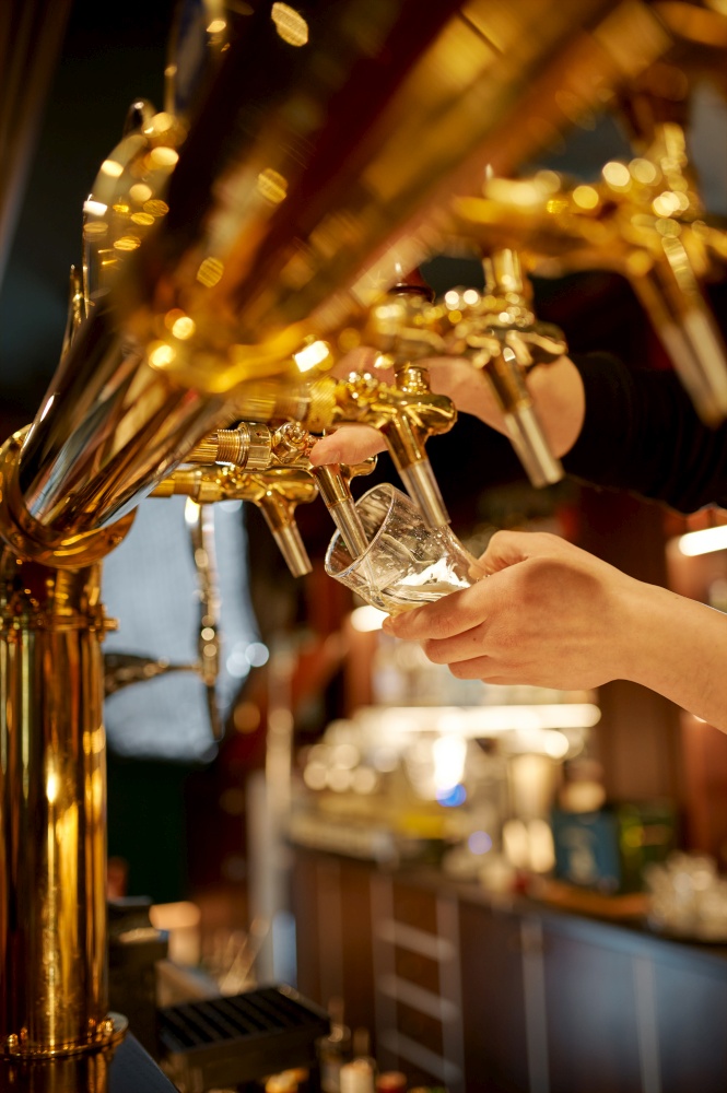 Bartender pours fresh beer into a glass. Friends leisures at the counter in bar, nightlife. Group of people relax in pub, night lifestyle, friendship, event celebration. Bartender pours fresh beer into a glass