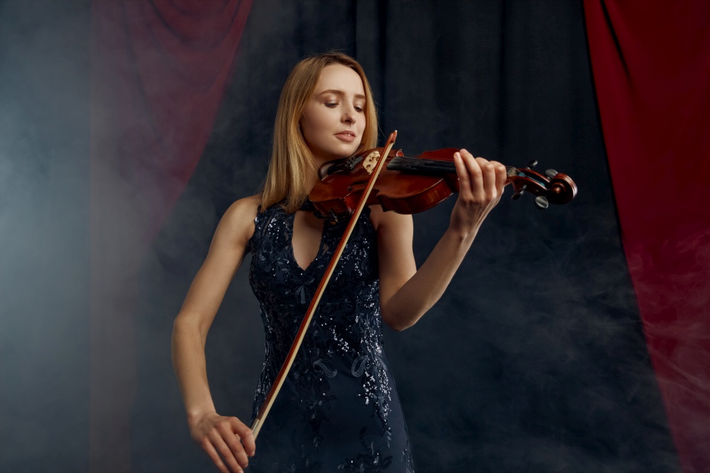 Female violonist with bow and violin, solo concert on stage. Woman with string musical instrument, musician play on viola. Female violonist with bow and violin, solo concert