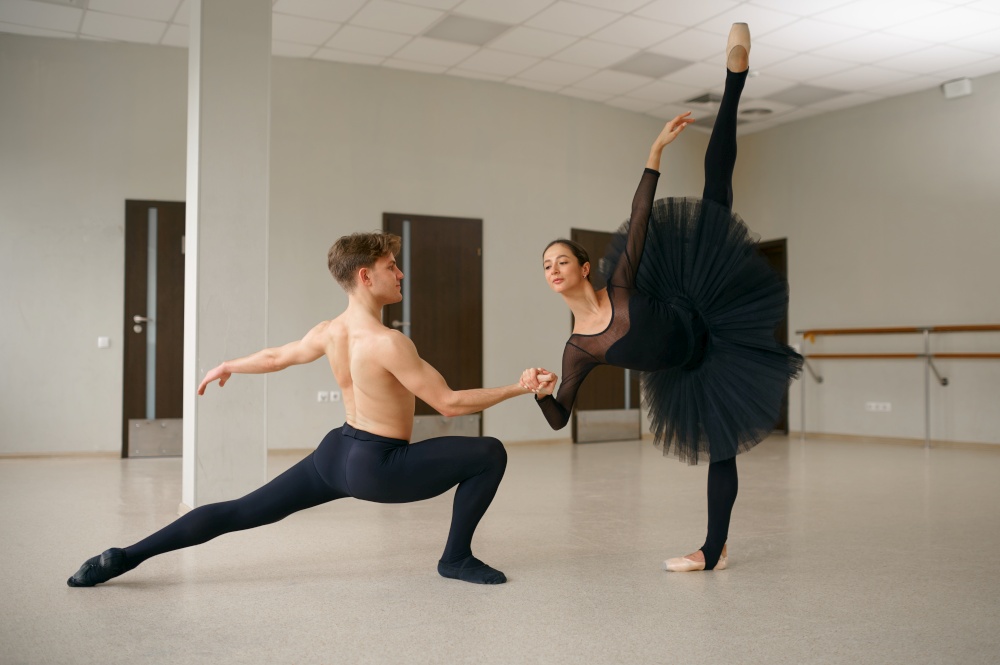 Female and male ballet dancers in action. Ballerina with partner training in class, dance studio interior on background. Female and male ballet dancers in action