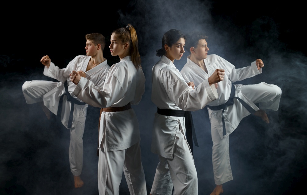 Four karate fighters in white kimono, group training, dark smoky background. Karatekas on workout, martial arts, fighting competition. Four karate fighters in kimono, smoky background